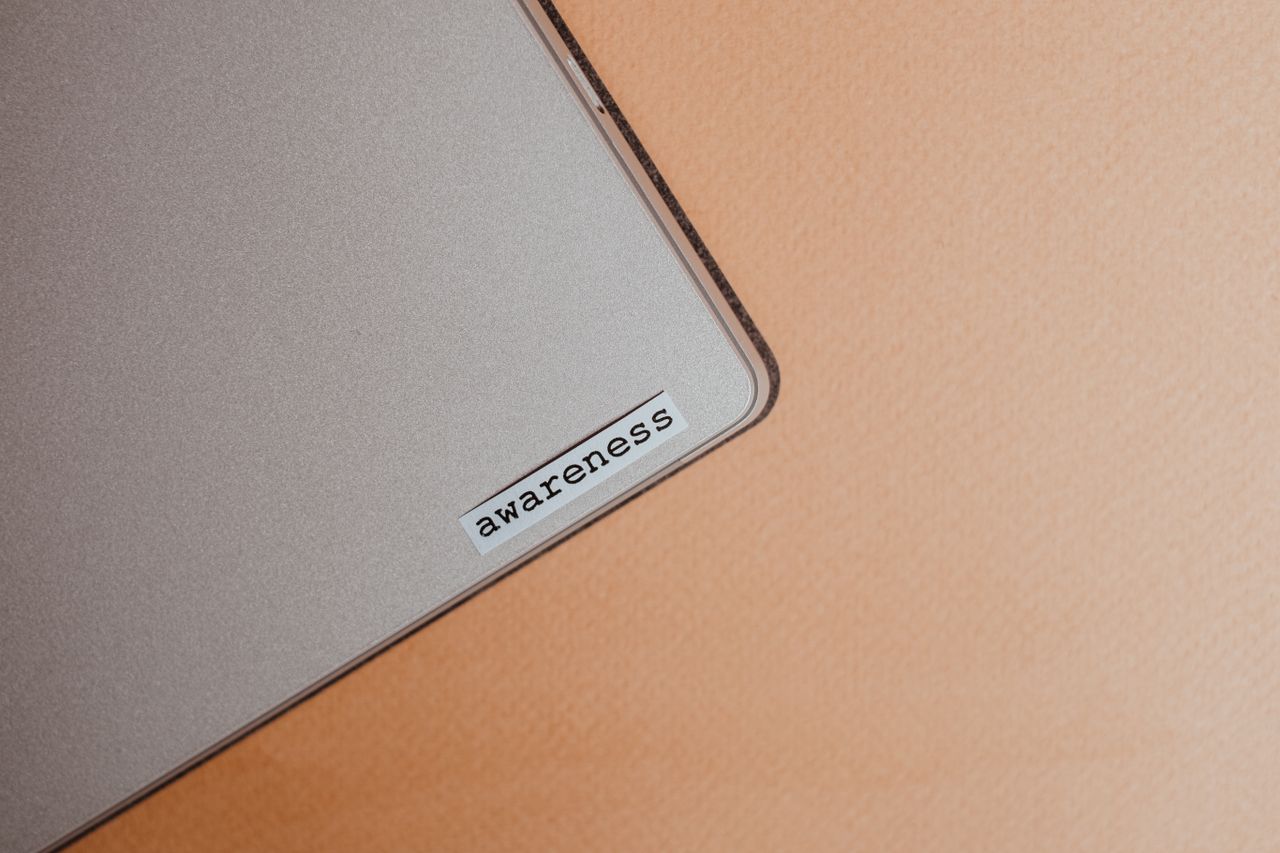 services-02 Close-up of a beige laptop with an awareness sticker, promoting mindfulness and digital organization.