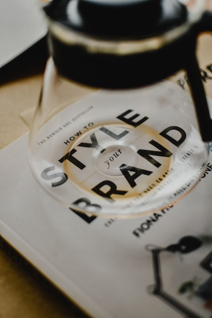 hero-img-01 A coffee pot rests atop a book titled How to Style Your Brand, capturing the essence of creative branding.